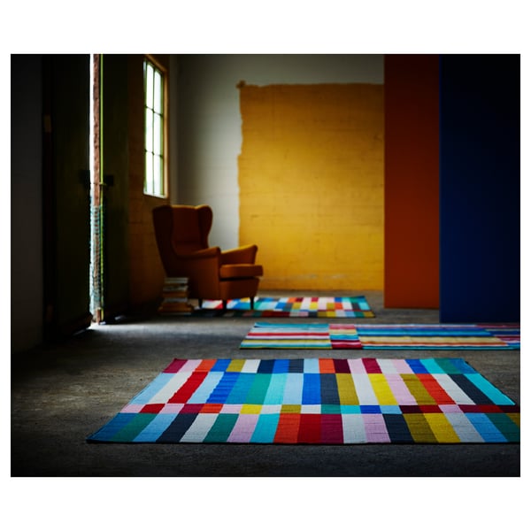 Multicoloured geometric rugs with horizontal stripes in red, blue, yellow, and green, handwoven from wool and cotton.