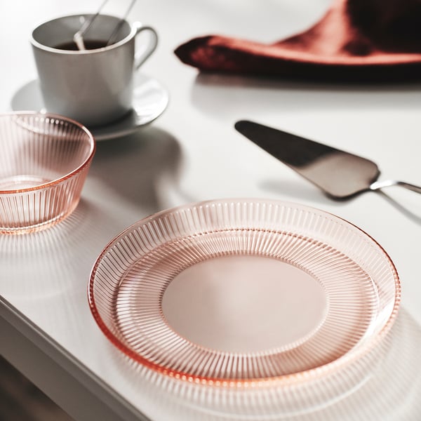 Pink glass dinnerware set: plate & bowl with ridged designs, stackable, near white mug.