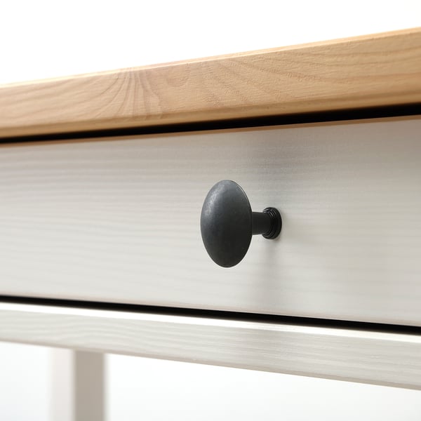 Close-up of sleek, modern desk with smooth wooden top and black round handle on drawer.
