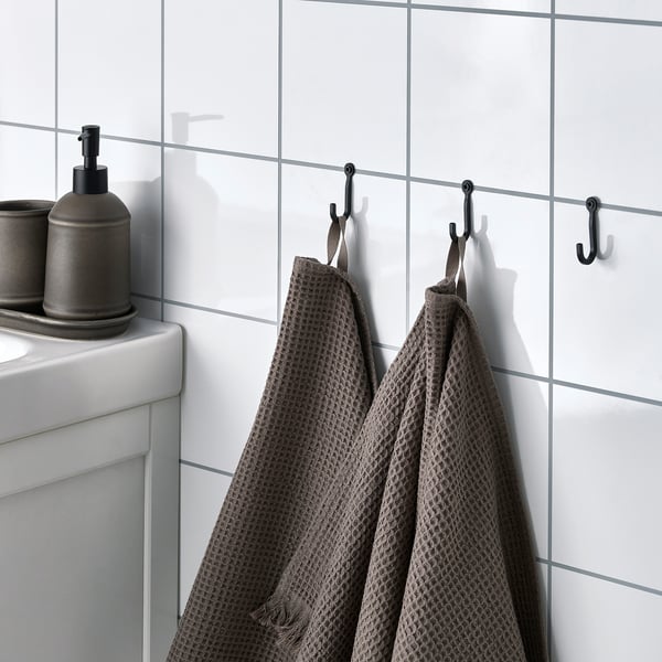 Small hooks hang towels near sink with dispensers.