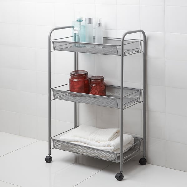 Silver HORNAVAN 3-tier metal bathroom trolley with black wheels holds towels, bottles, and jars; against white tiles.