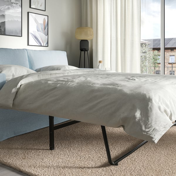 Modern sofa-bed with light grey cover; transforms into a bed.