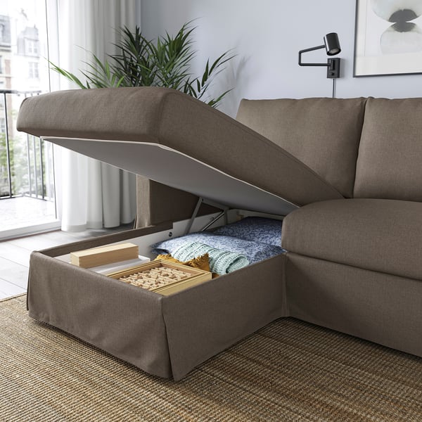 Modern sofa with a large built-in storage compartment in the chaise. The compartment is open, revealing blankets and a board game.