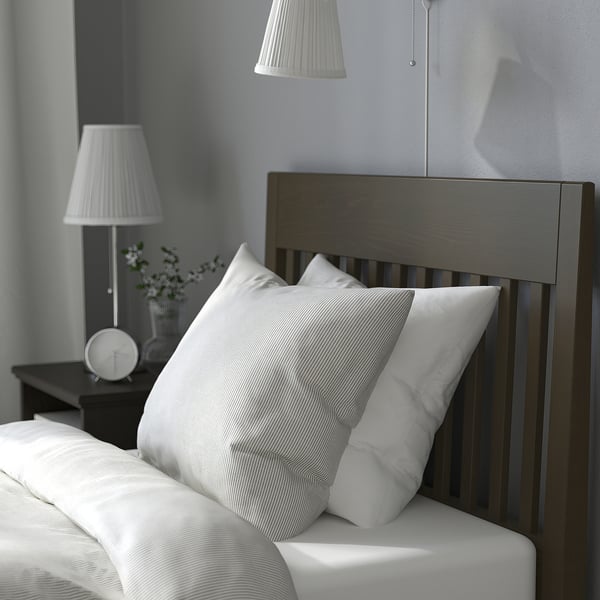 Modern bed with dark headboard, white pillows, and two lamps on a bedside table.