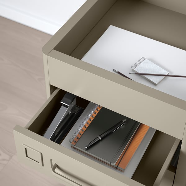 Beige desk drawer open with notebook, pen, showing soft-close feature.
