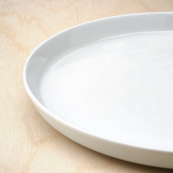 A pristine white porcelain dish on a wooden surface. The dishs smooth, even surface reflects light, showing its fine craftsmanship and quality.