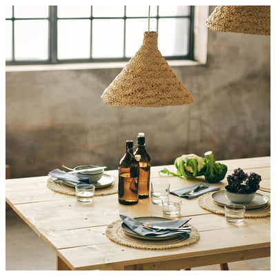 A rustic wooden table set with IKEA 365+ glassware, napkins, and fresh vegetables under woven pendant lights.