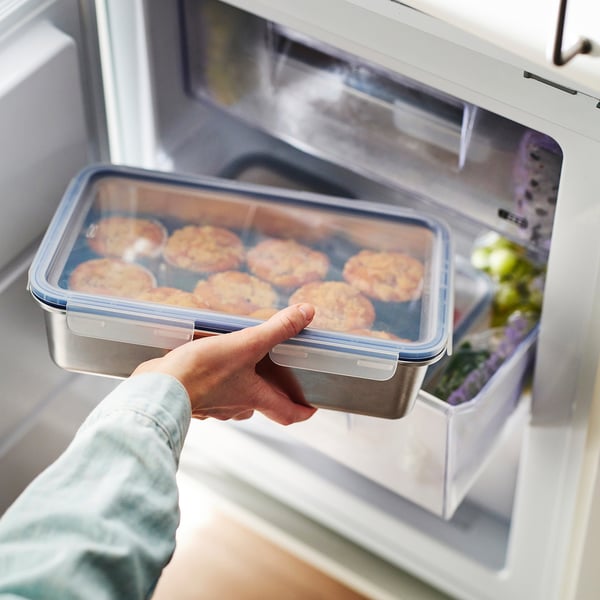 A hand holding a rectangular IKEA 365+ container with muffins, showcasing its leak-proof lid and transparency.