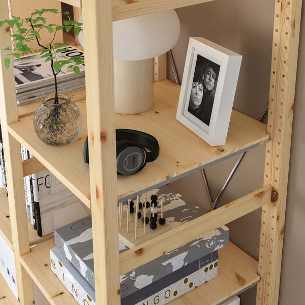 Wooden shelf unit with various items: photo, lamp, plant, headphones, and game board, showcasing versatile storage and personalization.