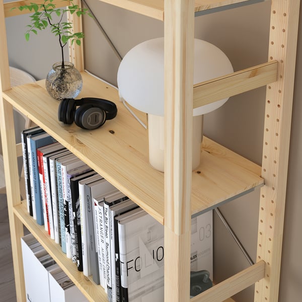 Wooden bookshelf with adjustable shelves, holding books, headphones, and a lamp.