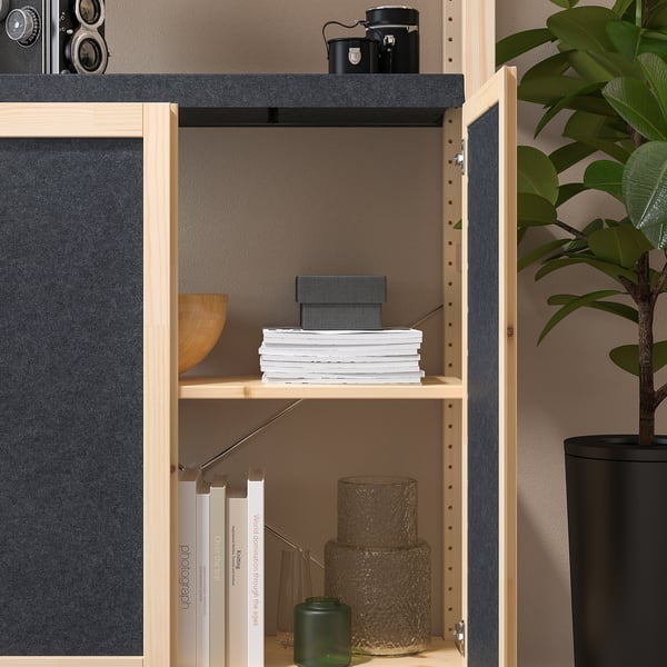 Wooden shelf unit with felt doors, holding books, vases, and a plant.