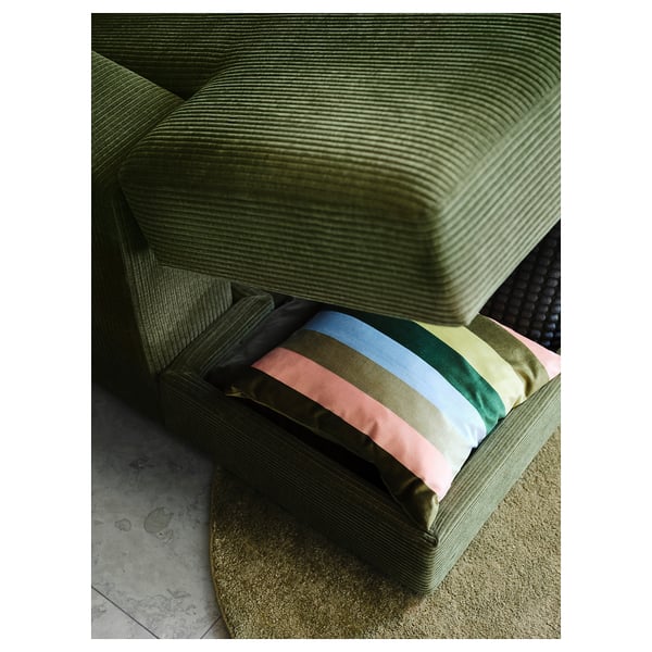 Green JÄTTEBO sofa with colourful striped pillow and textured rug.