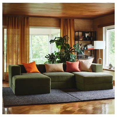 Cosy living room with JÄTTEBO green modular sofa, vibrant pillows, large plant, wooden decor, sunny window.