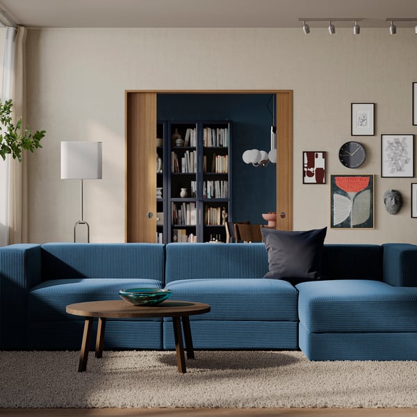 Modern living room with blue sectional, wooden table, and art.