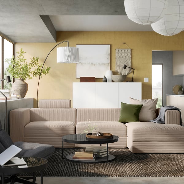 Modern living room with beige JÄTTEBO modular sofa, coffee table, plants, and artwork.