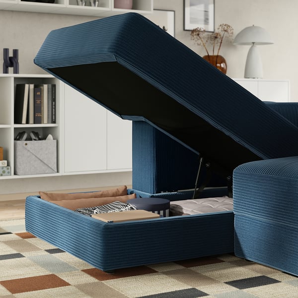 A modern blue sofa with storage chaise, open to expose cushions and storage.