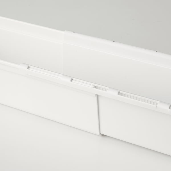 White extendable storage box, part of a modern organisation system. Shows part of a white box with grooves, indicating adjustability.