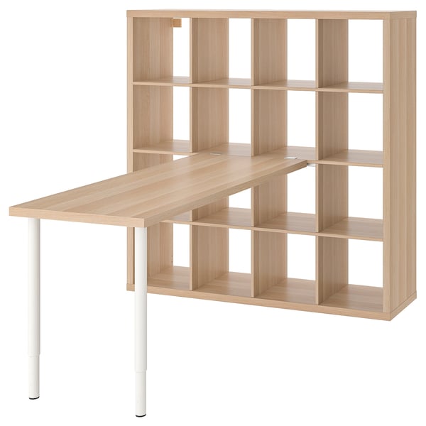 An ikea KALLAX shelving unit with a light wooden desk on top. It has multiple open cubes for storage.