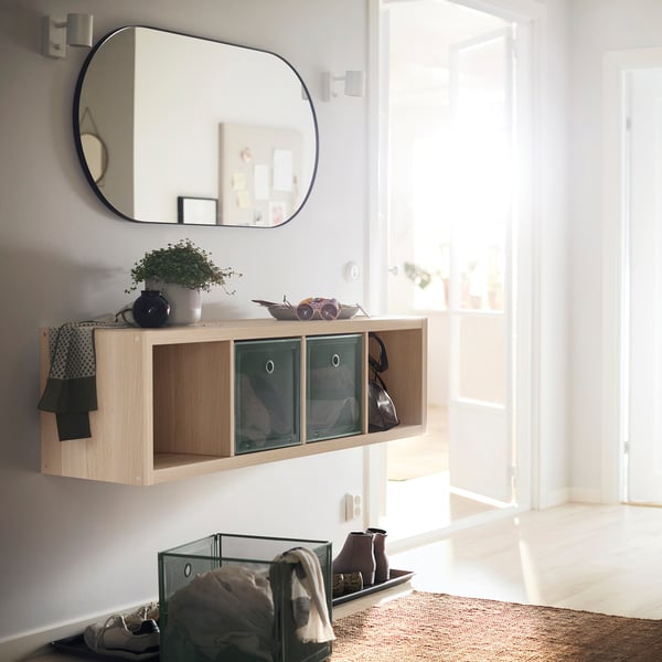 Modern entryway with light wood KALLAX shelf, green mesh drawers, mirror.