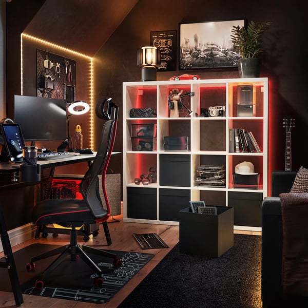Modern home office featuring a black and red KALLAX shelving unit with led lights, a sleek desk, and electronic equipment.