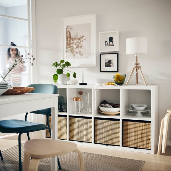 Living room with KALLAX shelving, blue & beige chairs, rug, art.