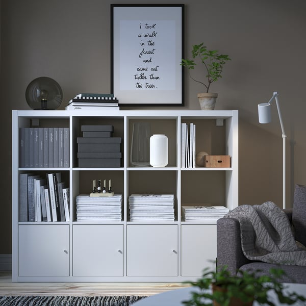 Modern living room with KALLAX bookshelf, lamp, sofa, and plant.