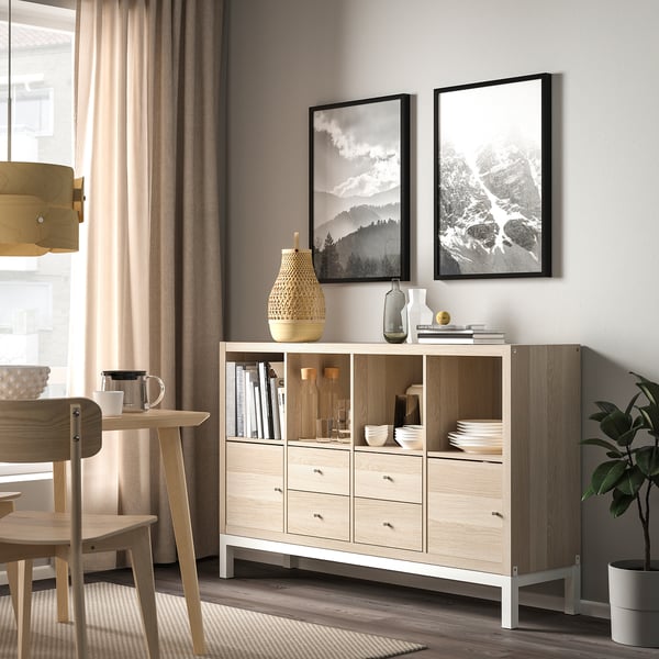 KALLAX sideboard: light wood, 6 drawers, 2 shelves. Decor & dining ware. Mid-wall height, between window & plant.