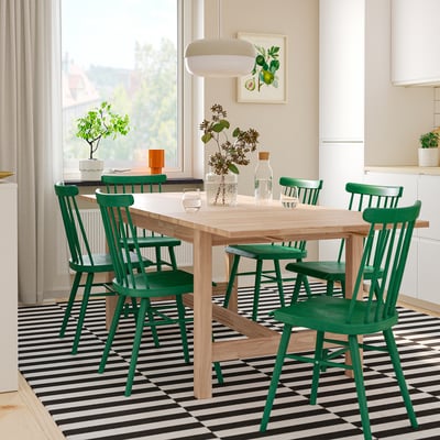 KARSKÄR wood table with green chairs, window, pendant light, rug, plants, vases, spindle backs.