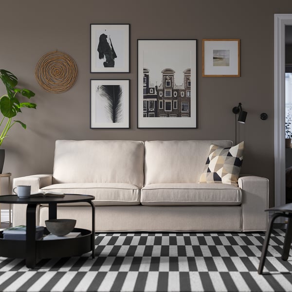 Modern living room with KIVIK sofa, art gallery wall, and chequered rug.