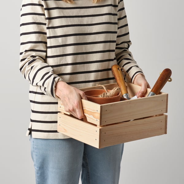 Person holding wooden box with handles, containing tools.