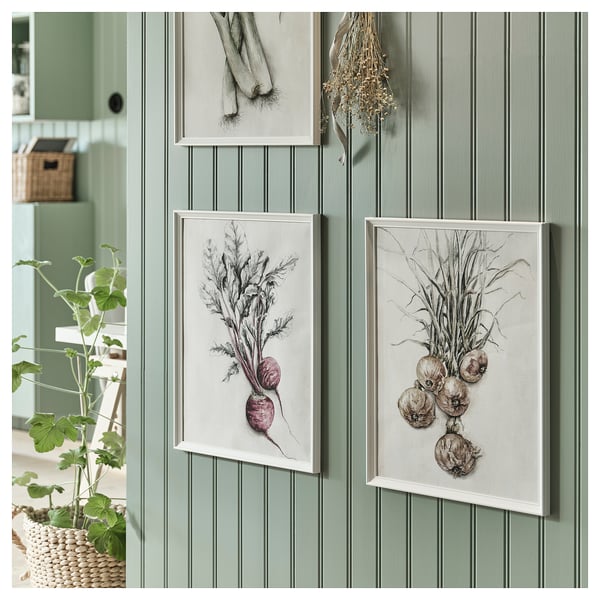 Three vegetable artworks hang on green wall. Left: potted plant. Centre: beet illustration. Right: onion drawing.