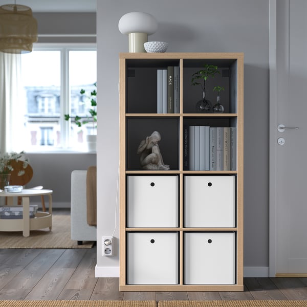 Modern living room with KUGGIS storage unit. White drawers, books, sculpture. Minimalist design by window.