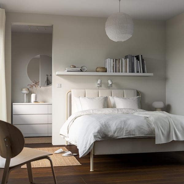 Minimalist bedroom with LACK shelf, books, decor, bed, dresser, mirror, chair, and pendant light.