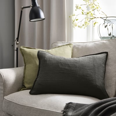 Modern sofa with LAGERPOPPEL anthracite cushion, rectangular, textured. Larger than adjacent pillows, complemented by a grey throw.