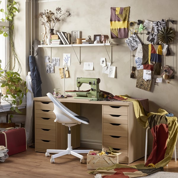 A home office with LAGKAPTEN desk, ergonomic chair, vintage sewing machine, and mood boards.