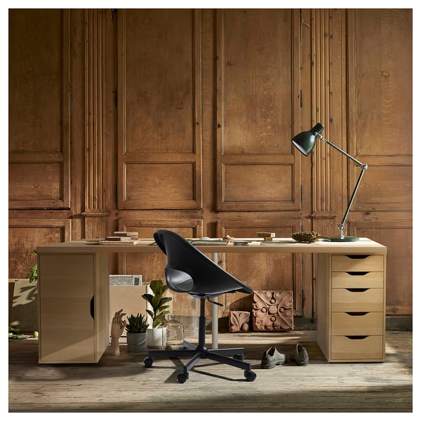 Modern home office setup with LAGKAPTEN desk, black chair, and green lamp against wooden panel wall.