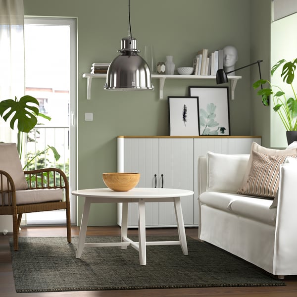 Cosy living room with green rug, white table, chairs, and decor.