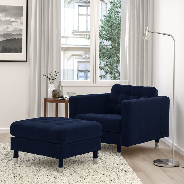 Modern living room with blue velvet chair, lamp, and city view.