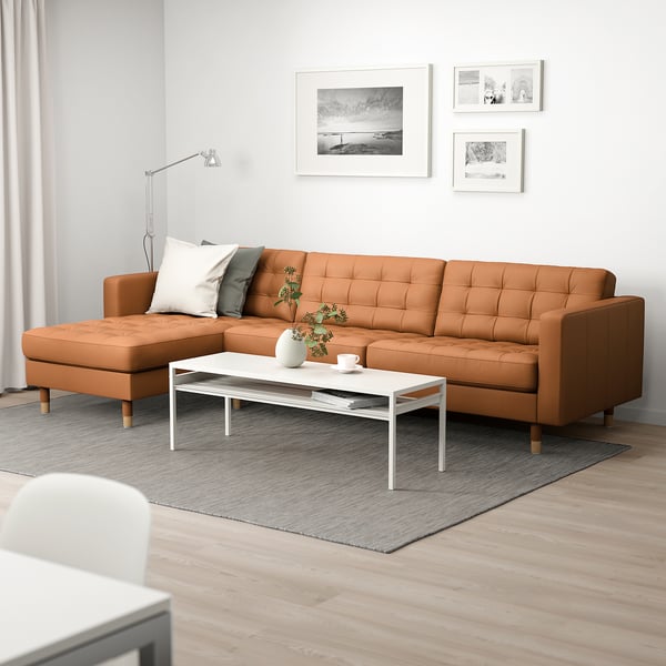 Modern living room with l-shaped sofa, coffee table, rug, art, lamp, and window.