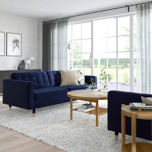 Modern living room with blue sofa, coffee table, and accent chair, well-lit by large window.
