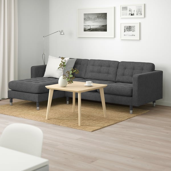 Modern living room with dark sofa, light coffee table, white walls & b&w pictures.