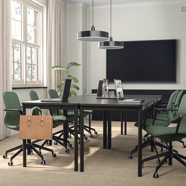 Modern meeting room with green LÅNGFJÄLL chairs, black table, and stylish lights. Professional setting with tv and window.