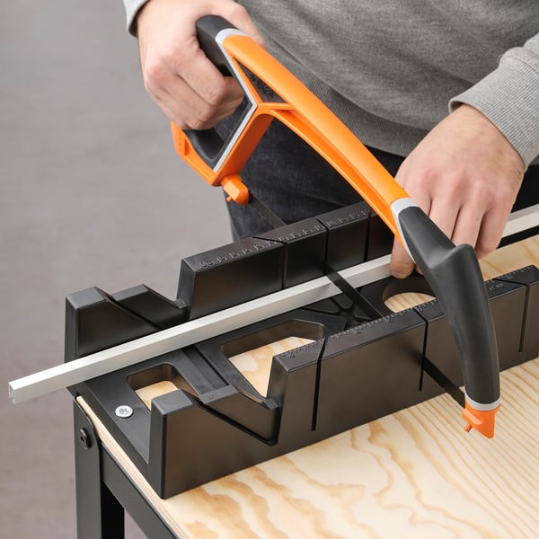 Cutting metal rail with orange-handled tool for custom sliding doors.