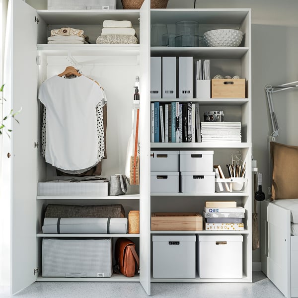 Organised closet with hanging clothes, stacked storage boxes, and office supplies on shelves.