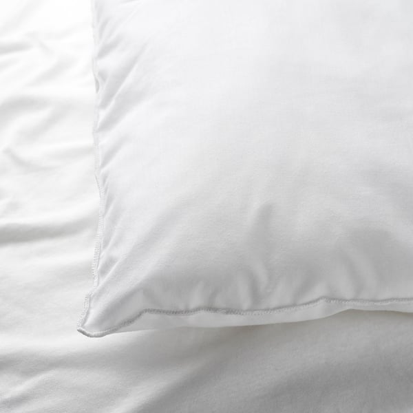 Close-up of soft, white cotton pillowcase, neatly stitched, resting on a bed.