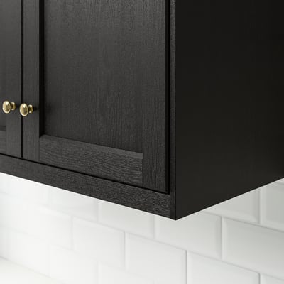 Black wooden cabinet with intricate grain detail and gold knobs.