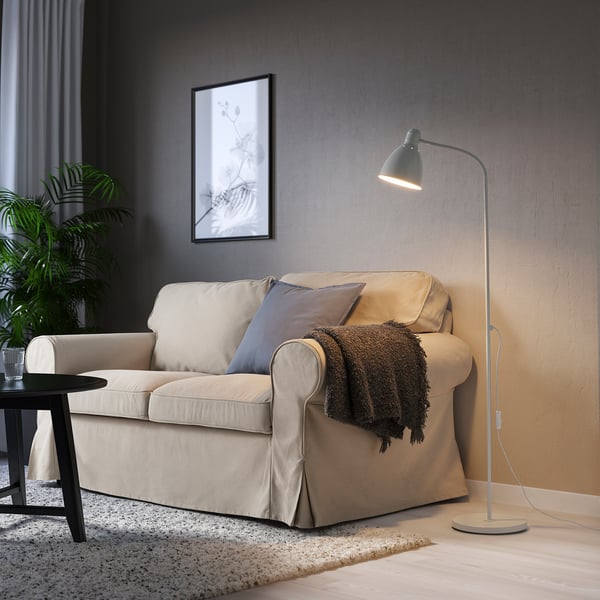 A cosy living room with a beige LERSTA floor lamp beside a sofa, a rug, and a small table with a glass.