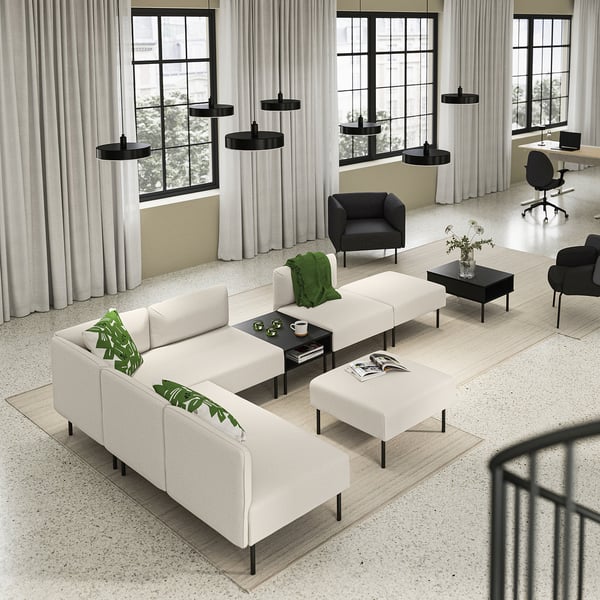 Modern office lounge featuring LILLEHEM white modular sofa, black coffee tables, and dark armchairs, accented with green decor.