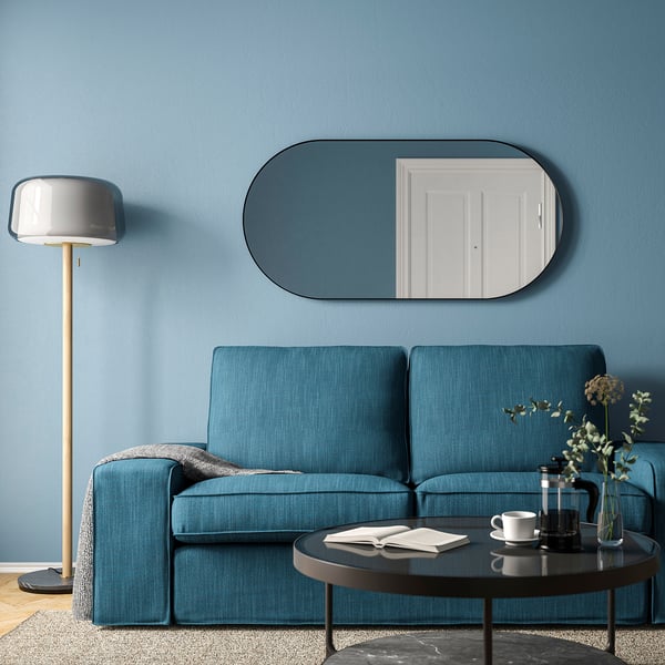 A modern living room with blue sofa, LINDBYN mirror, and floor lamp.