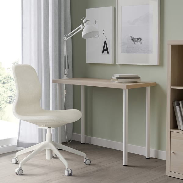 LINNMON desk, white-wood, minimalist. Fits under wall frames with rolling chair, lamp, grey curtains.